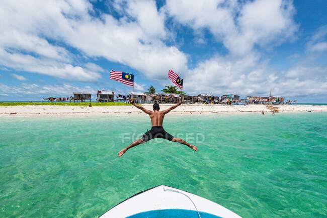 A boatman is making a high jump from boat to the sea while heading to Gusungan Island Sabah — Stock Photo