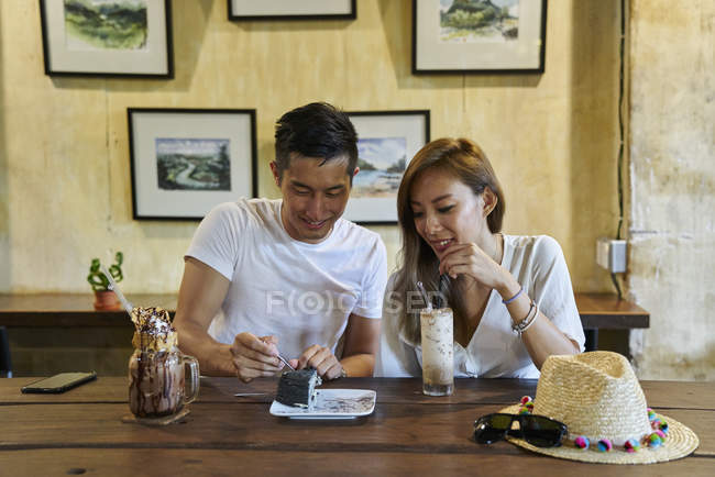 Happy young asian couple sitting together in cafe — Stock Photo