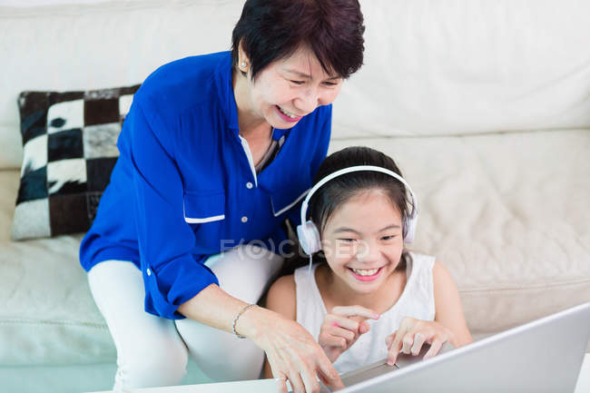 Grand-mère et son petit-enfant utilisent un ordinateur portable ensemble . — Photo de stock