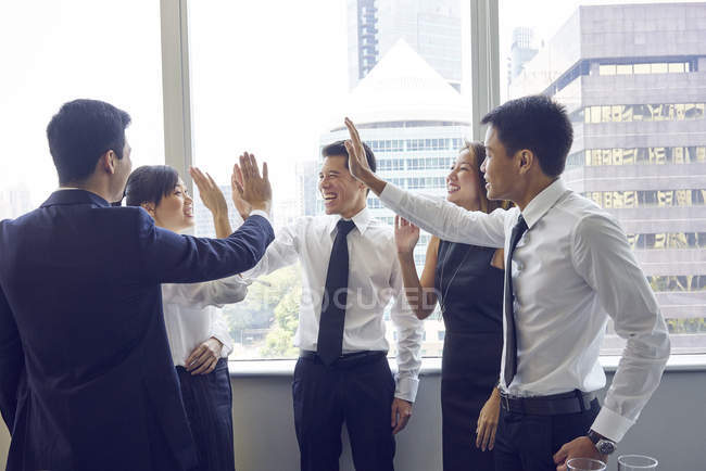 Молоді азіатські бізнесмени дають п'ять в сучасному офісі — стокове фото
