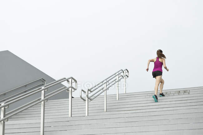 Una joven asiática, corredora femenina está subiendo una escalera en Singapur . - foto de stock