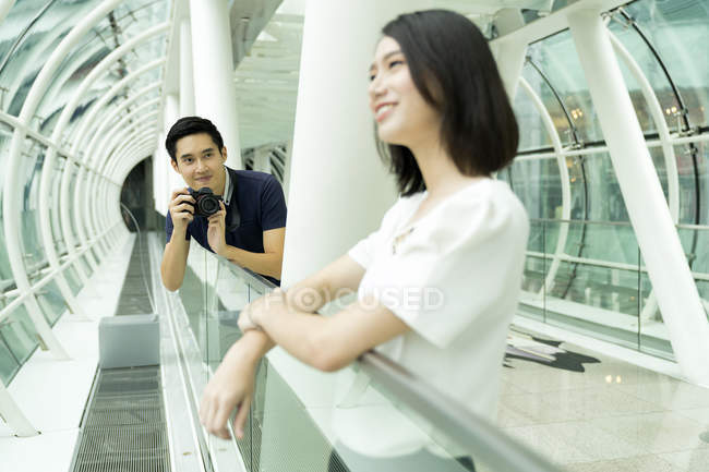 Young attractive asian couple together with camera in mall — Stock Photo