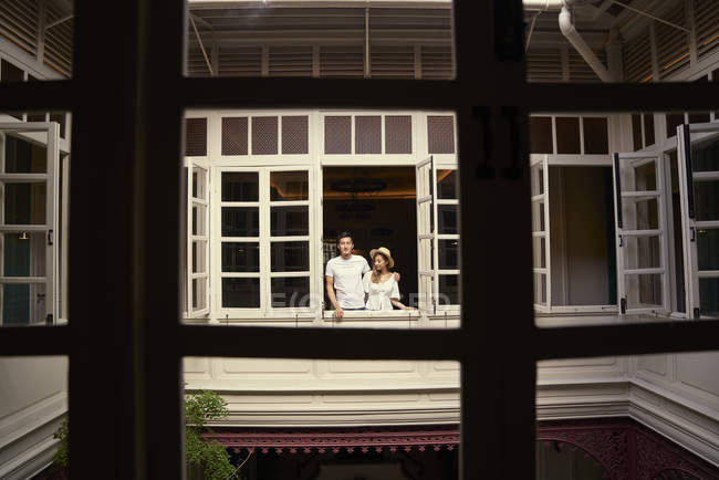 Young attractive asian couple together looking out of window — Stock Photo