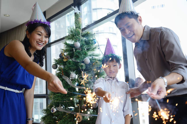 Happy asian family celebrating Christmas together at home with sparklers — Stock Photo