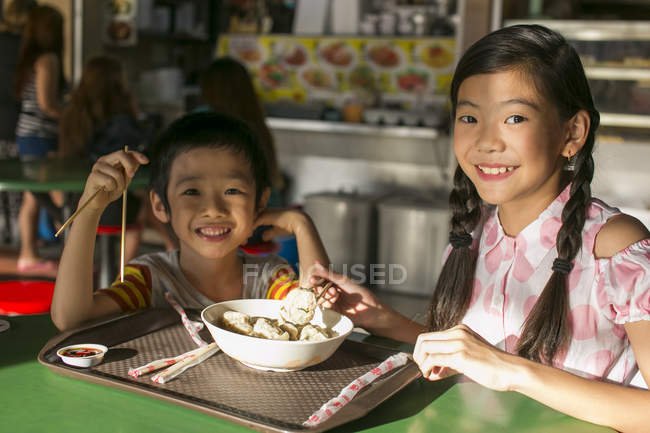 Двое счастливых молодых людей с детьми едят в кафе — стоковое фото