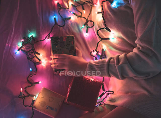 Обрезанный образ женщины расслабляющей дома с рождественской гирляндой — стоковое фото