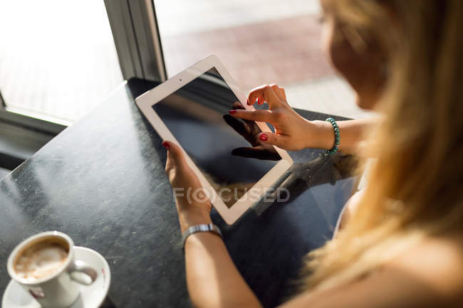 Портрет красивої молодої жінки, що використовує свій цифровий планшет у кафе . — стокове фото