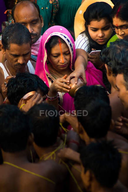Durante el festival de Chat pooja, la mujer está ofreciendo leche al sol naciente y los devotos están tomando bendición tocando la leche porosa. - foto de stock