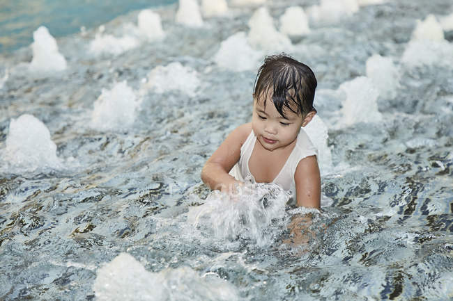 Young little asian toddler girl playing in waves — Stock Photo