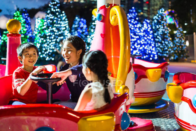 Happy asian siblings spending time together in amusement park at christmas — Stock Photo