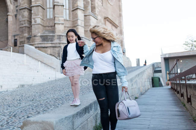 Felice giovane madre con sua figlia a piedi in città — Foto stock