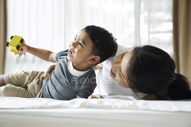 Asiatico madre e figlio giocare con giocattoli su il letto — Foto stock