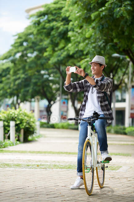 Asian smiling tourist cycling around and taking photos — Stock Photo