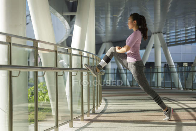 Eine junge asiatische Frau dehnt sich vor ihrem täglichen Lauftraining in der Stadt Singapore. — Stockfoto