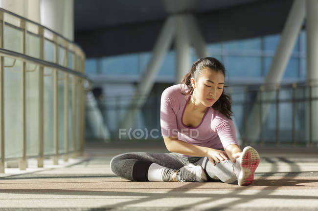 Una joven asiática se está estirando antes de su entrenamiento diario en la ciudad de Singapores . - foto de stock