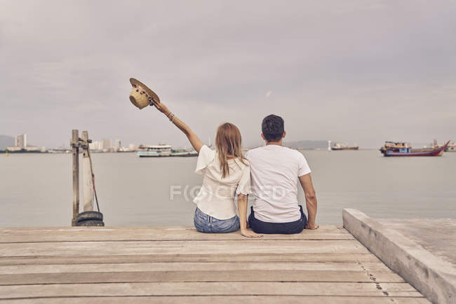 Rückansicht eines jungen attraktiven Paares zusammen auf der Seebrücke — Stockfoto