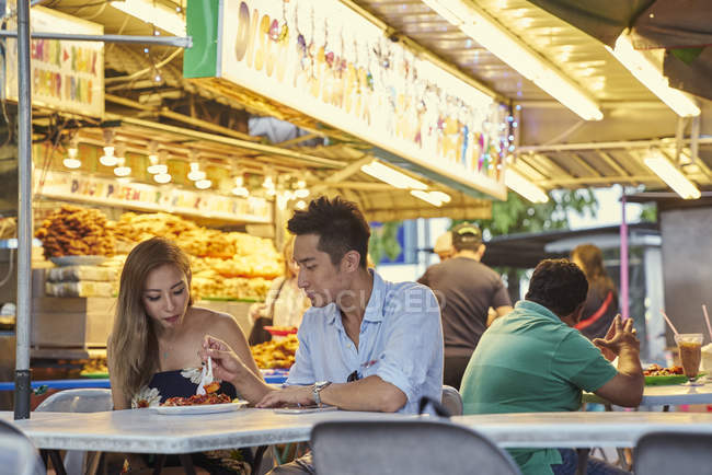 Happy young asian couple sitting together in street cafe — Stock Photo