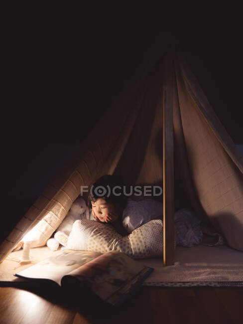 Nettes kleines Mädchen liest im Zelt ein Buch — Stockfoto