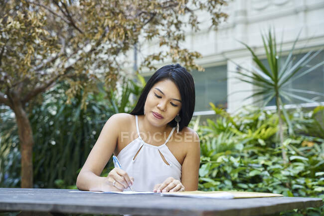 Alegre mujer malaya feliz escribiendo en documentos - foto de stock