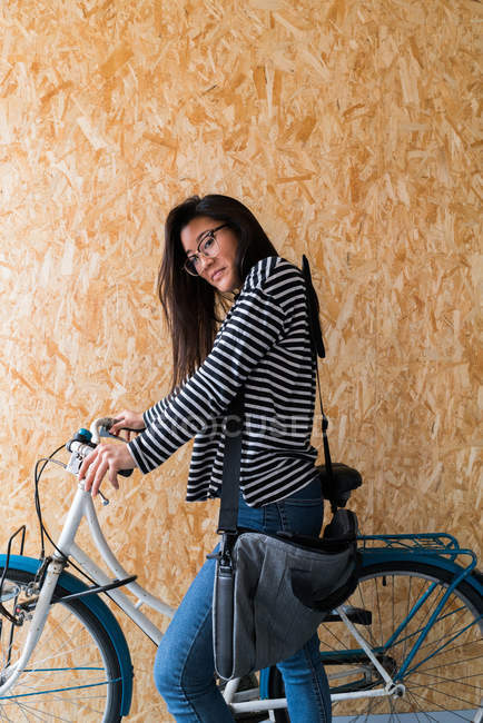 Вид сбоку на молодую женщину с велосипедом — стоковое фото