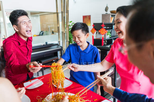 Feliz asiático familia juntos comer en casa - foto de stock