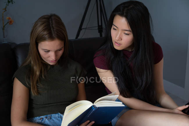 Mujer china buscando un libro con su amigo . - foto de stock