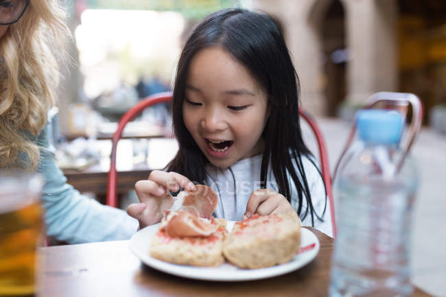 Feliz chica china mirando su pan con jamón - foto de stock