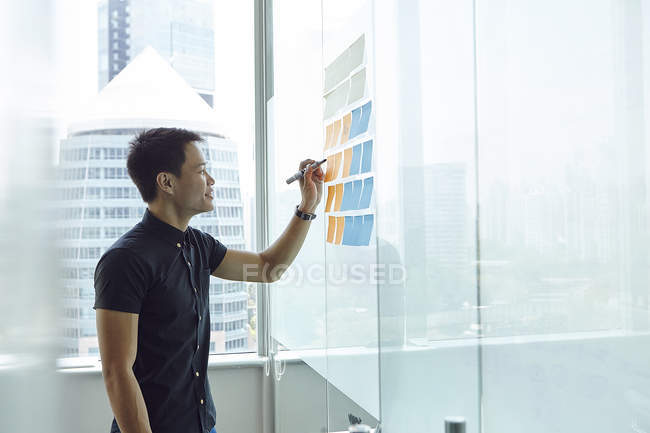 Jeune homme d'affaires asiatique au travail dans un bureau moderne — Photo de stock