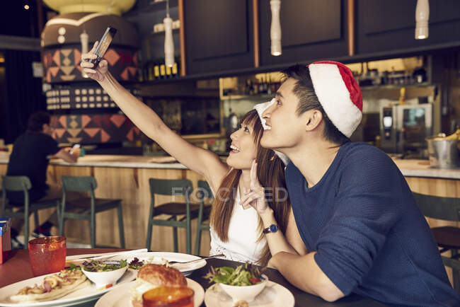 Un jeune couple asiatique se prend en santa chapeaux — Photo de stock