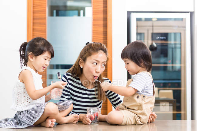 Mujer disfrutando de una merienda saludable con sus hijos . - foto de stock