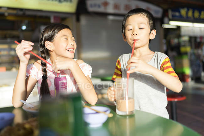 Niños asiáticos beben con pajitas - foto de stock