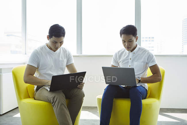 Jovem asiático homens de negócios trabalhando com laptops no escritório moderno — Fotografia de Stock