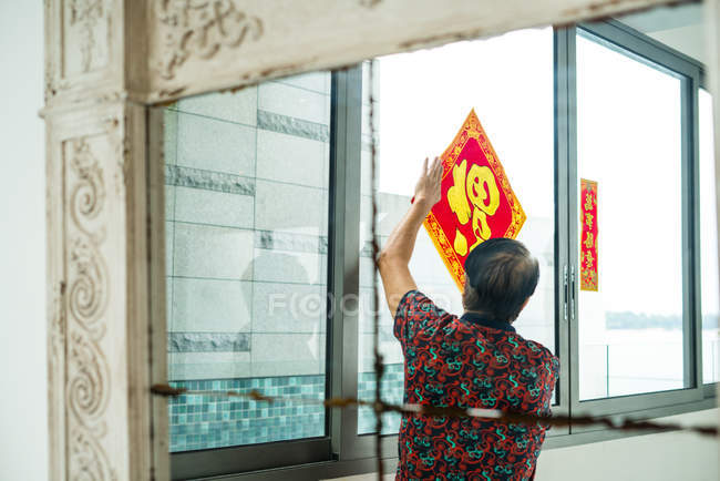 Vista posteriore di vecchio asiatico uomo decorazione finestra — Foto stock
