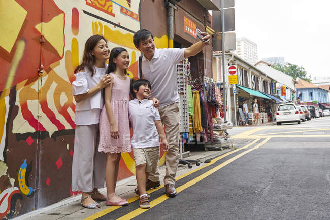 Feliz joven asiático familia juntos en calle y tomando selfie - foto de stock