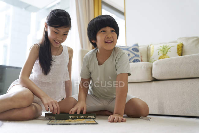 Happy young asian family together, children playing scrabble at home — Stock Photo