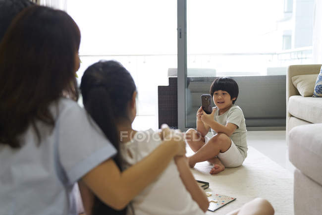 Feliz joven asiático familia juntos, chico tomando foto en casa - foto de stock