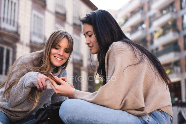 Друзі, дивлячись на свій смартфон на вулицях міста Мадрид — стокове фото