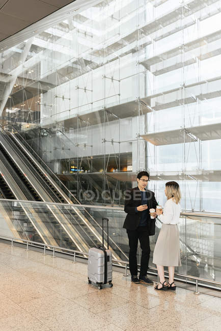 Успешная бизнес-азиатская пара вместе с кофе в аэропорту — стоковое фото