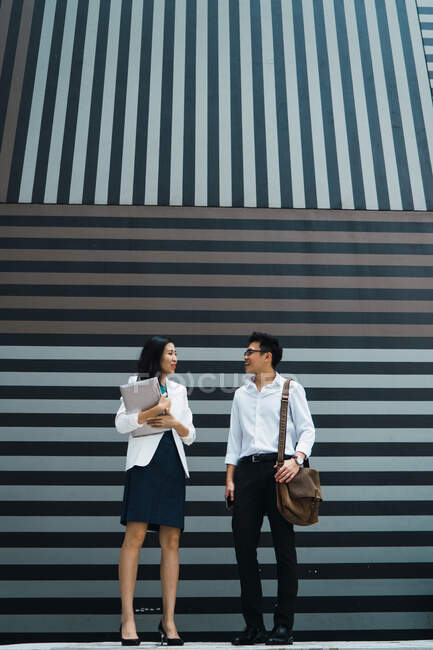 Молода азіатська ділова пара стоїть біля офісної стіни — стокове фото