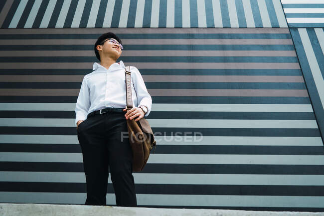 Молодий азіатський бізнесмен в місті позує біля будівлі — стокове фото