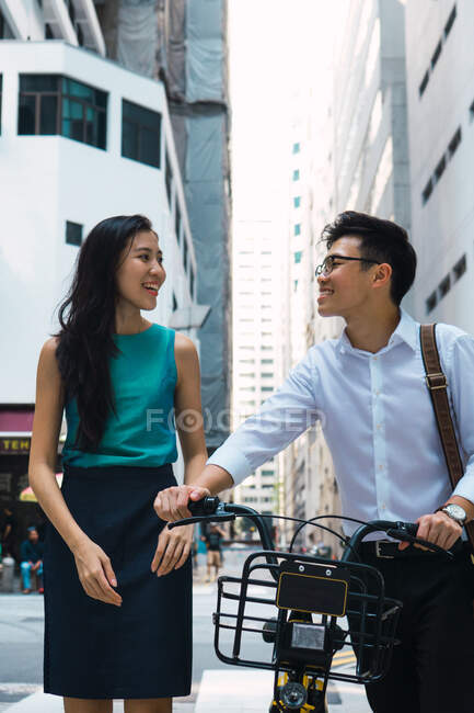 Pareja joven asiática de negocios que camina con bicicleta - foto de stock