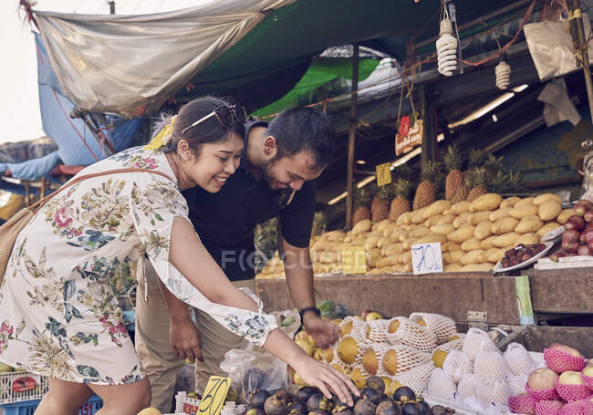 Jeune couple naviguant dans un stand de fruits à Koh Chang, Thaïlande — Photo de stock