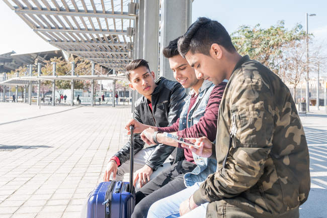 Amigos indios turistas esperando en una estación de metro de Barcelona para el tren con teléfono móvil - foto de stock