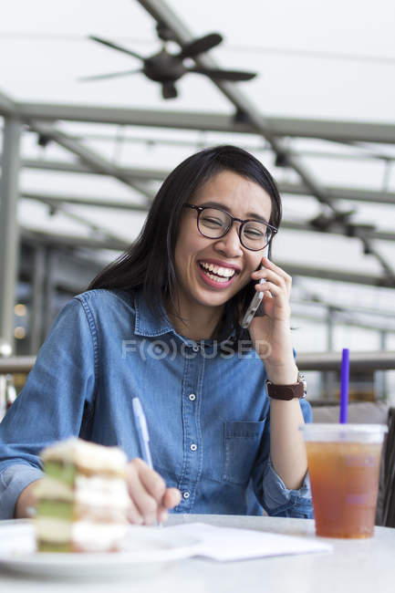Mujer joven anotando algo de información en un café . - foto de stock