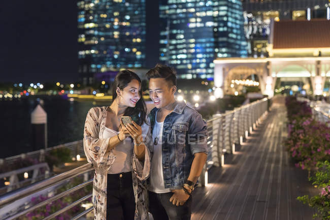 Jovem casal brincando com o smartphone na cidade urbana — Fotografia de Stock