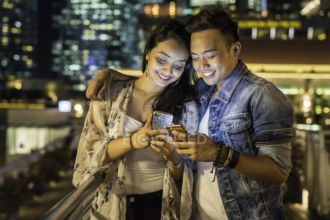 Jovem casal brincando com o smartphone na cidade urbana — Fotografia de Stock
