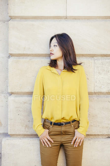 Pretty chinese woman posing against wall — Stock Photo