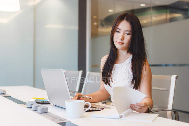 Молода жінка працює на ноутбуці в сучасному офісі — стокове фото