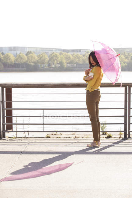 Mujer china con paraguas rosa posando a la cámara y tomando selfie - foto de stock