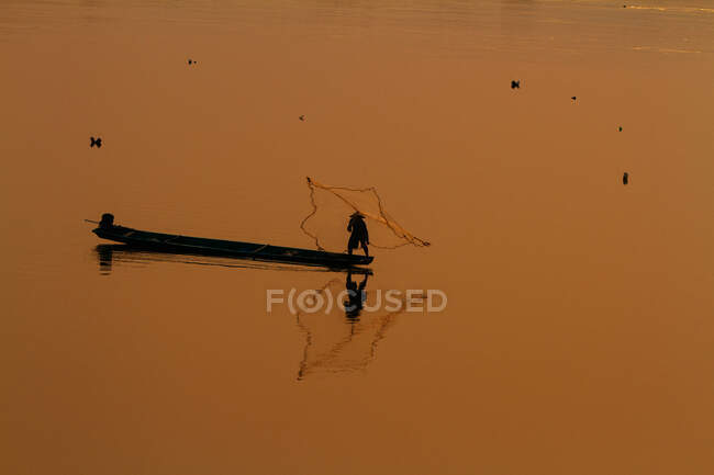 Pescador solitario lanzando su red - foto de stock